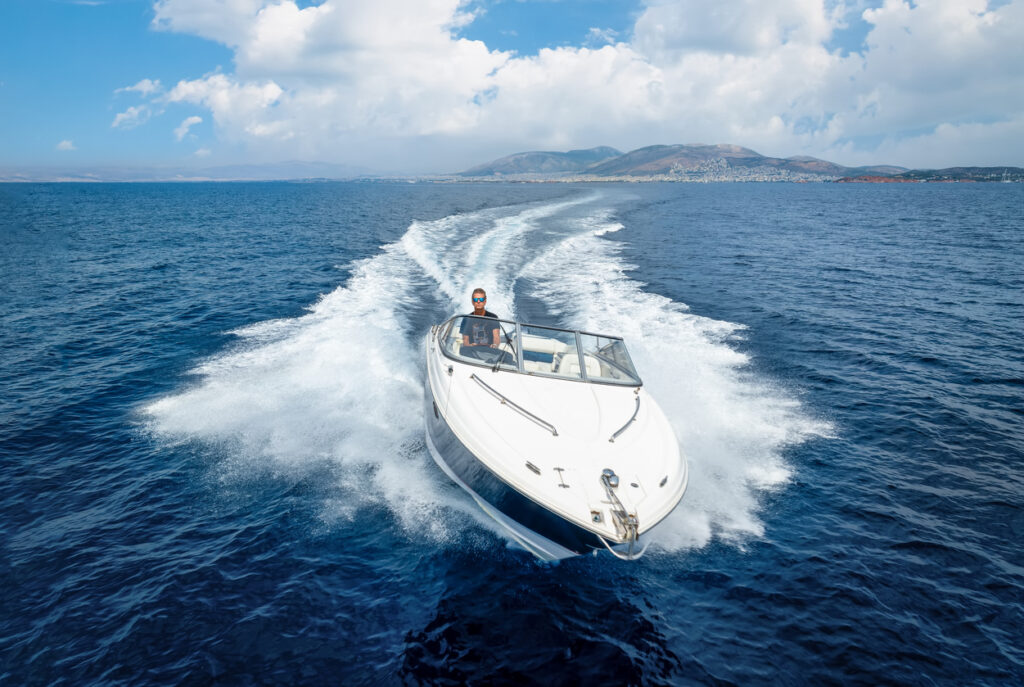 Best boat insurance: Aerial front view of a speedboat cruising over the sea during sunset time